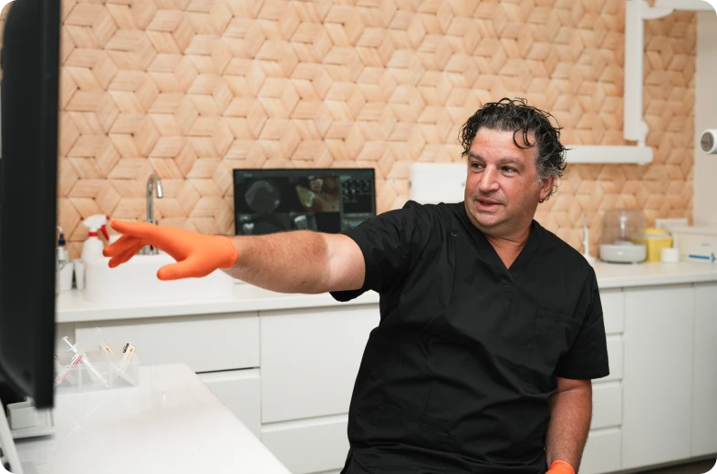 Endodontiste en consultation pointant un écran de diagnostic dans un cabinet dentaire moderne à Paris 16