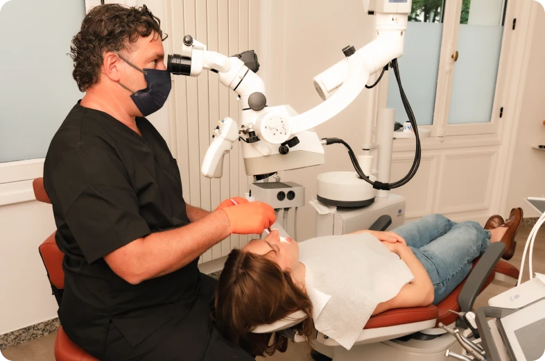 Endodontiste réalisant un traitement de canal sous microscope opératoire sur un patient allongé, Paris 16